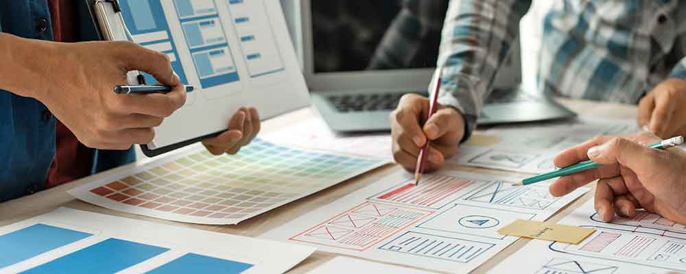 men creating story boards with paper & colored pencils